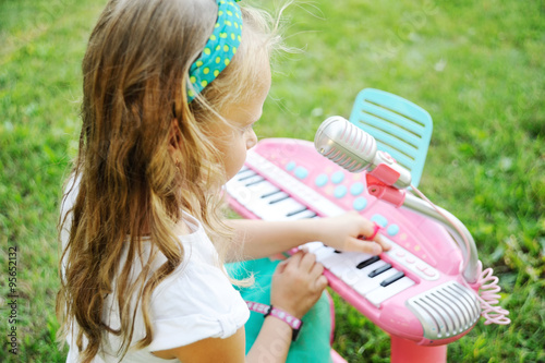 Child little girl playing on a toy piano