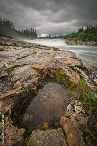 Laksfossen in Norway, a large water filled rock hole fills the foreground photo