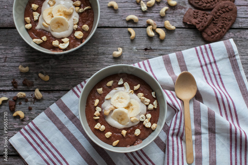 Chocolate cereal with bananas and nuts on the table with a wooden spoon