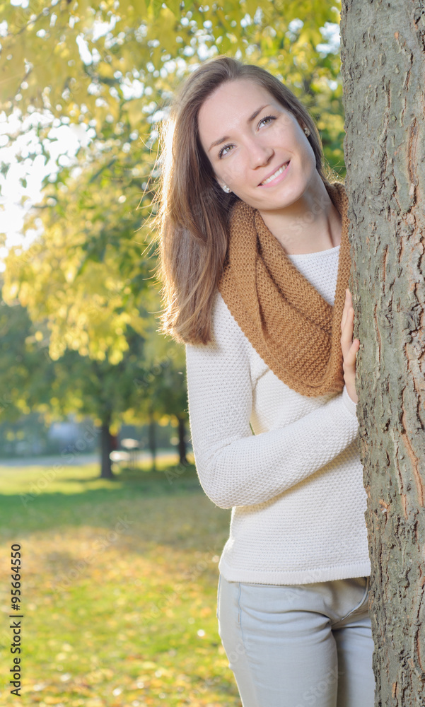 Young woman standing behind tree outdoor in park Young woman standing behind tree outdoor in park
