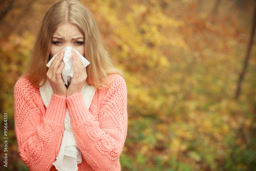 Sick ill woman in autumn park sneezing in tissue. Sick ill woman in autumn park sneezing in tissue.