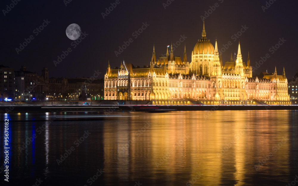 Fototapeta premium Budapest at night, Parliament building reflected in Danube river, full moon on sky