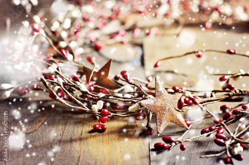 Christmas wreath with red and white berries and rusty metal stars, toned image, selective focus