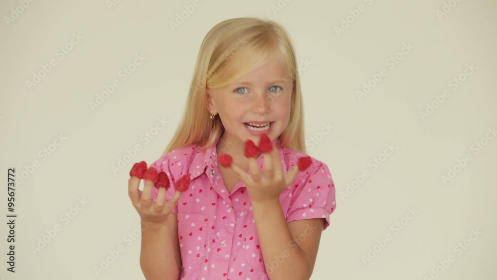 Cute little girl eating raspberries from top of her fingers and smiling Cute little girl eating raspberries from top of her fingers and smiling