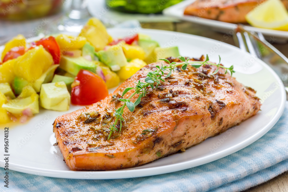Spice grilled salmon with mango-avocado salsa on a white plate Spice grilled salmon with mango-avocado salsa on a white plate