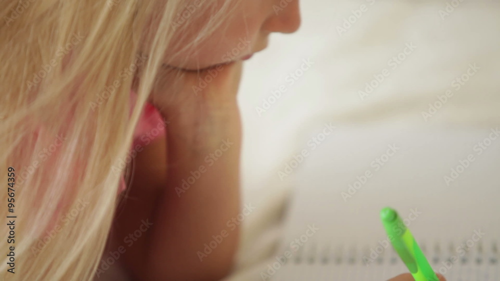 Funny little girl drawing in notebook and smiling at camera