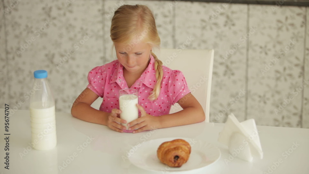 Funny little girl sitting at kitchen table drinking milk and smiling Funny little girl sitting at kitchen table drinking milk and smiling