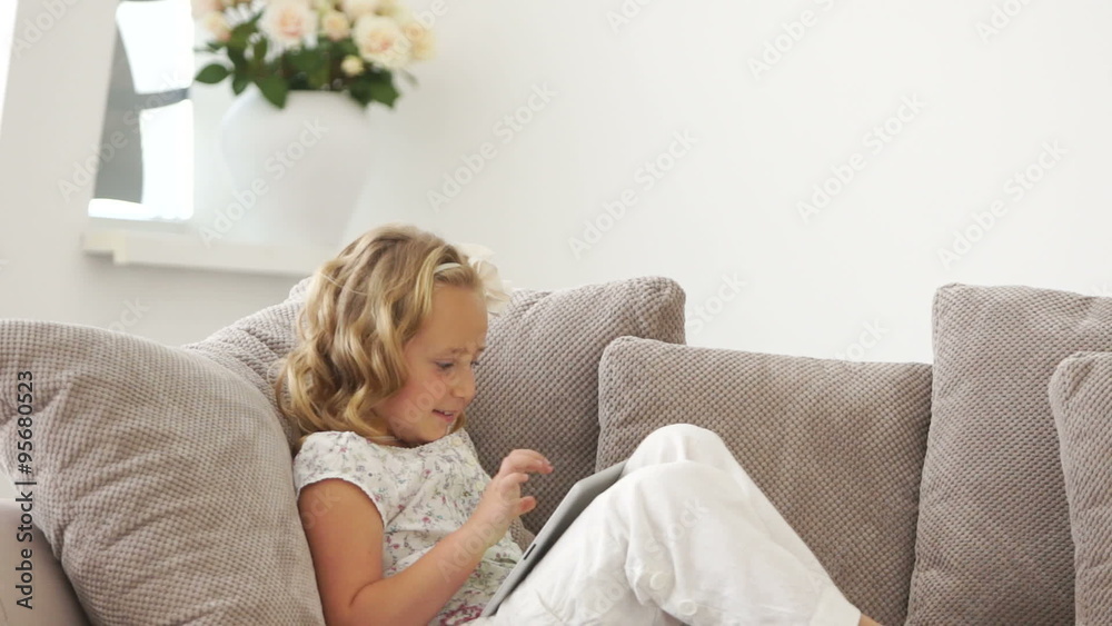 Little girl sitting on sofa with tablet pc Little girl sitting on sofa with tablet pc