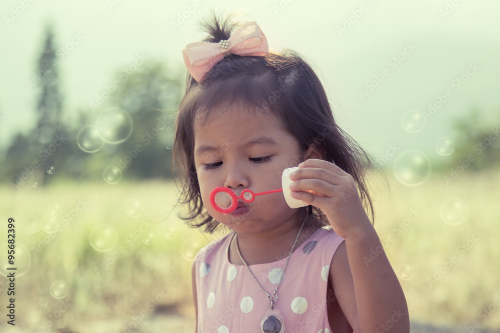 Child cute little girl blowing a soap bubbles in the park Child cute little girl blowing a soap bubbles in the park