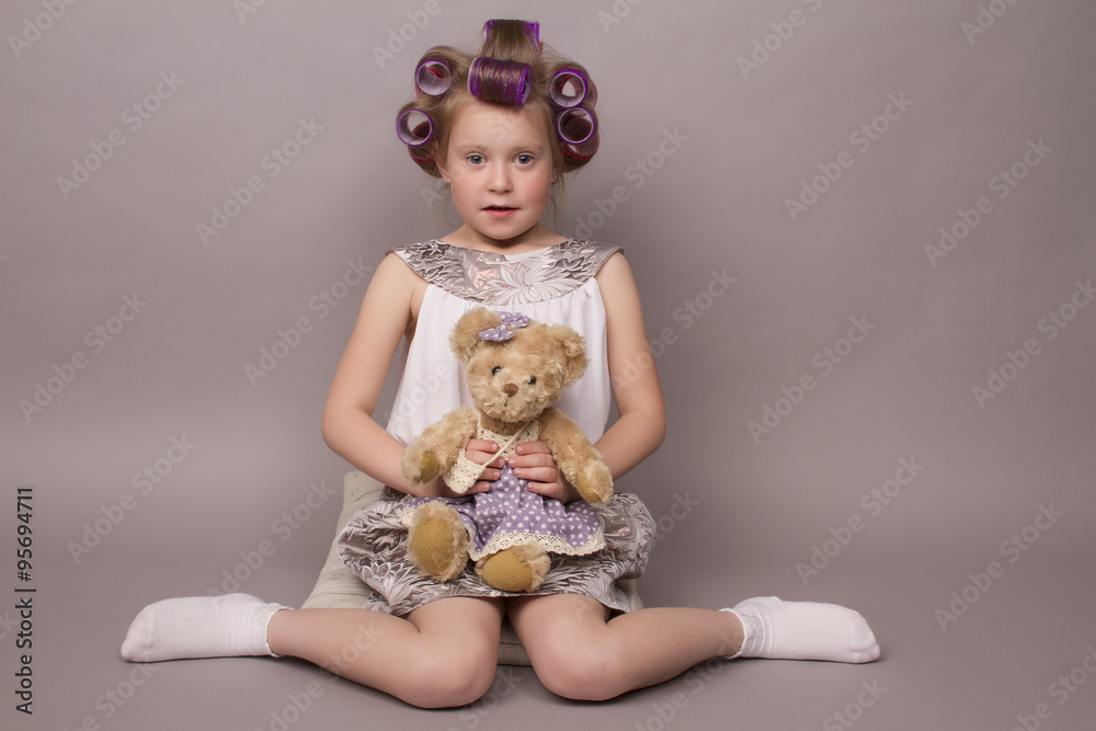 the little girl in hair curlers looks in the camera and sits