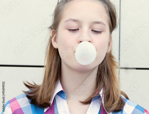 Portrait teen girl inflates a bubble of gum photo