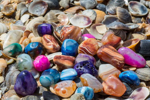 Multicolored agates with seashells on the beach
