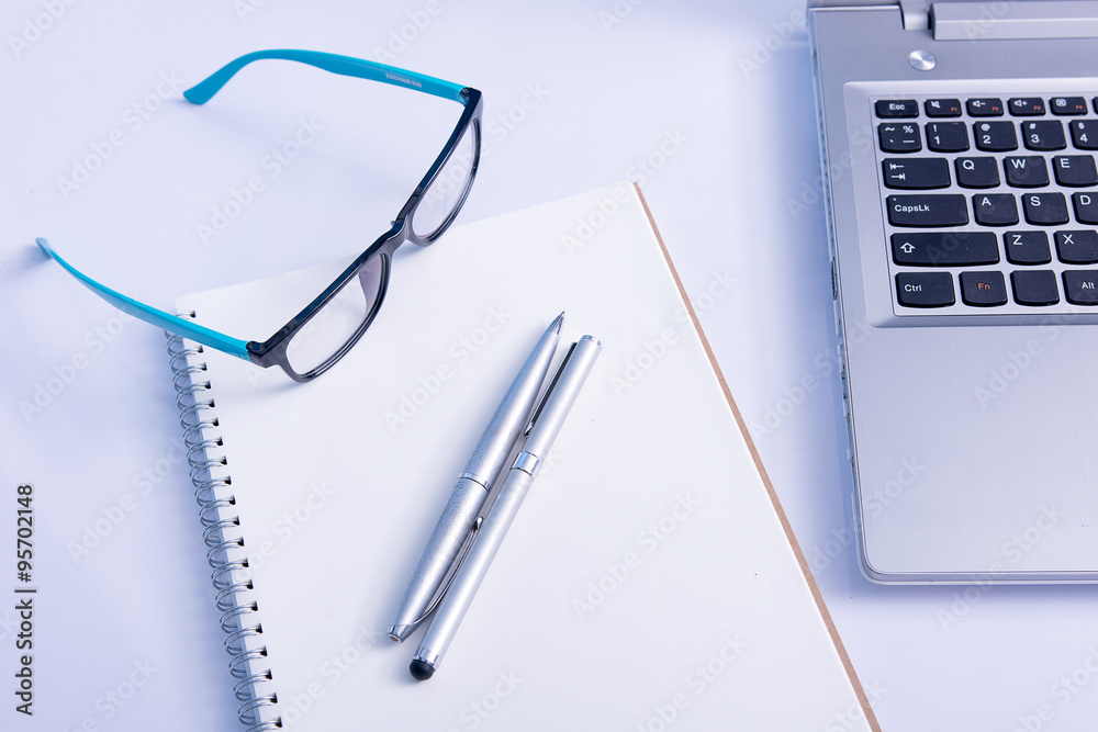 Glasses and blank notebook and laptop in the office Glasses and blank notebook and laptop in the office