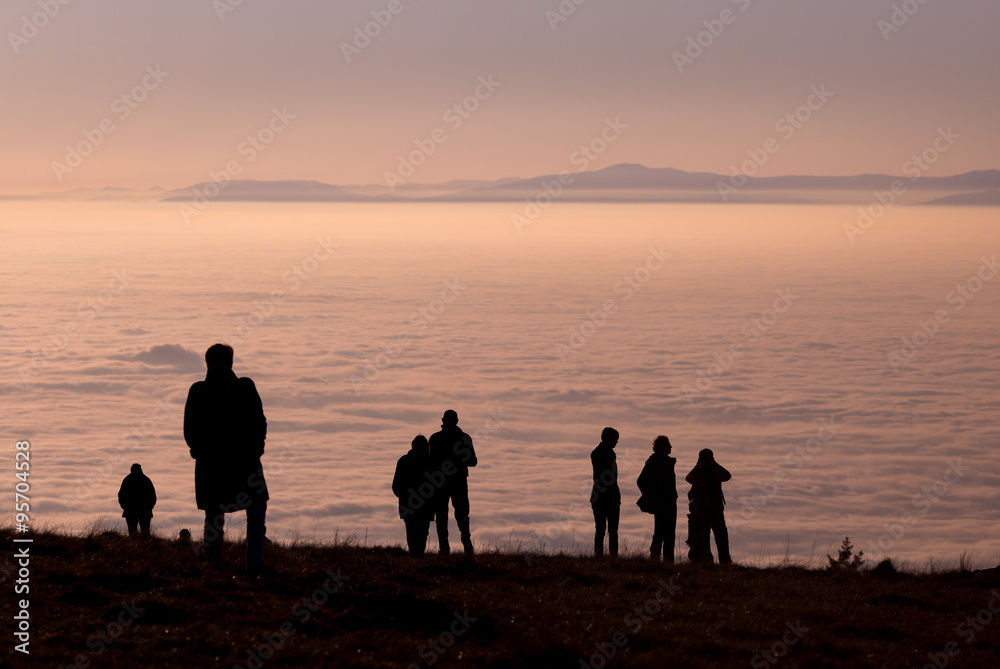 silhouetted people above inversion fog