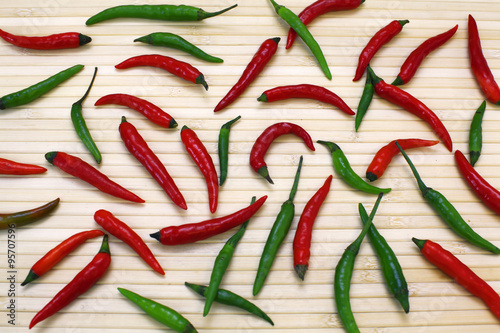 Red and green hot chili peppers over bamboo background. Image of natural materials. Eco style.