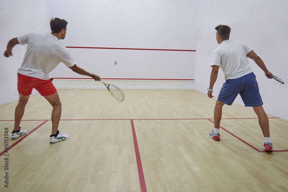 Two best friends playing squash indoors