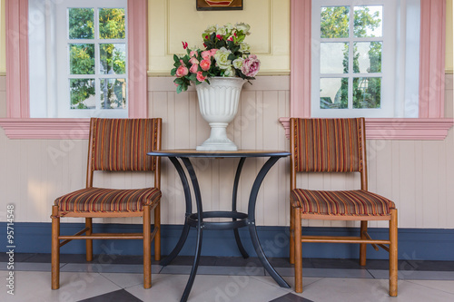 Two chairs and table with bouquet of flowers in vase on a patio