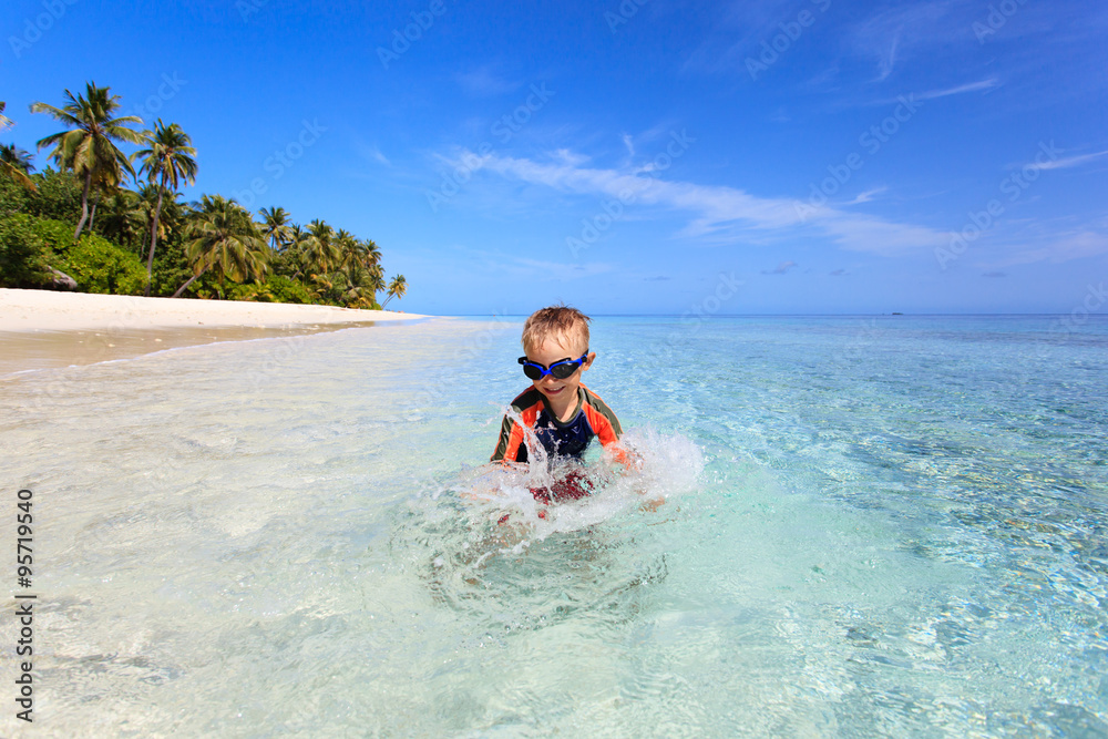 happy little boy swimming on tropical beach