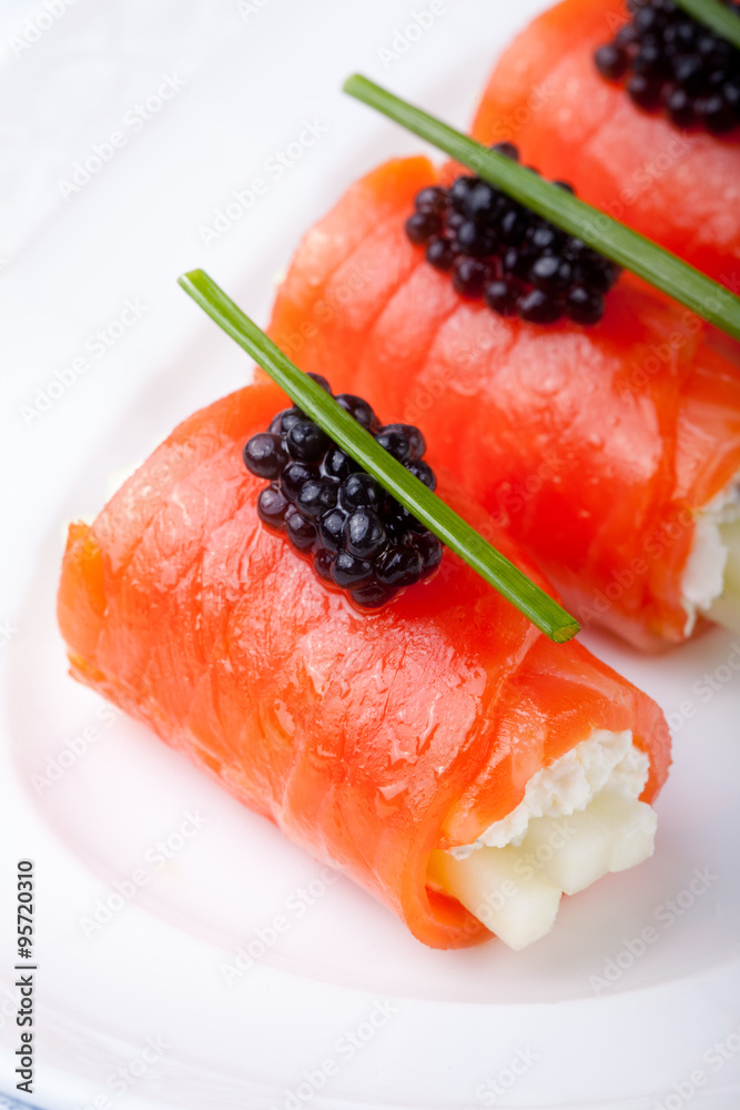 Smoked salmon rolls with cream cheese, black caviar