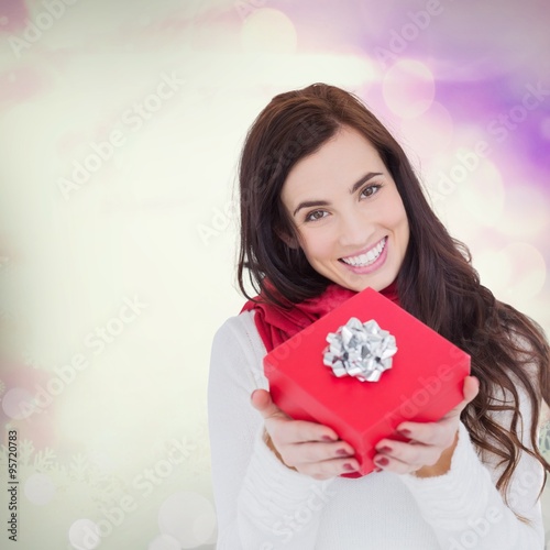 Composite image of happy brunette showing red gift with a bow 