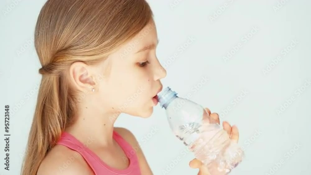 Closeup portrait sportswoman girl child opening bottle of water and drinking water at camera Closeup portrait sportswoman girl child opening bottle of water and drinking water at camera