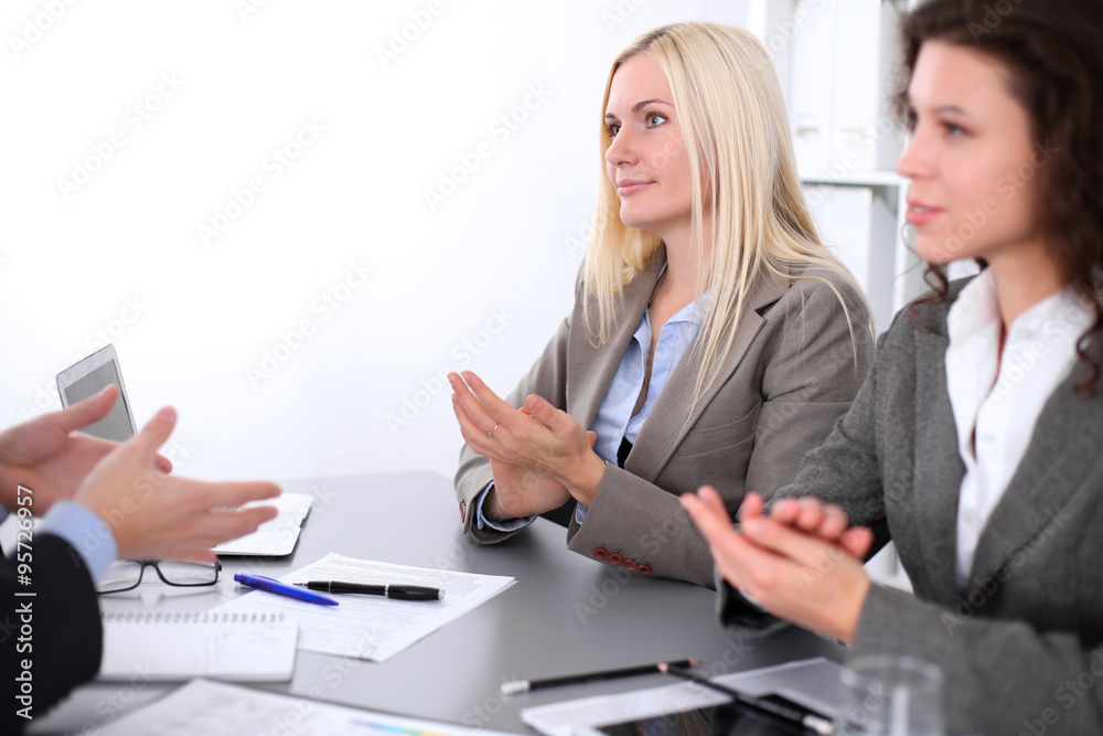 A group of business people applauding at meeting on the background of office. Focus on a beautiful blonde A group of business people applauding at meeting on the background of office. Focus on a beautiful blonde