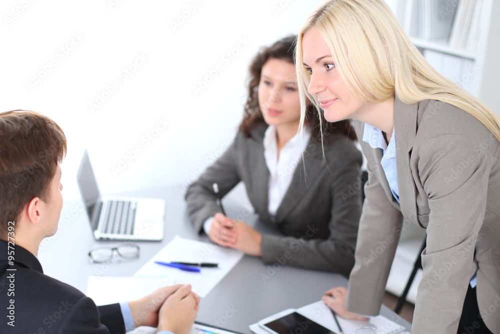 A group of business people at a meeting on the background of office. Focus on a beautiful blonde A group of business people at a meeting on the background of office. Focus on a beautiful blonde