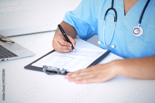 Portrait of unknown male surgeon doctor holding his stethoscope and filling up medical prescription
