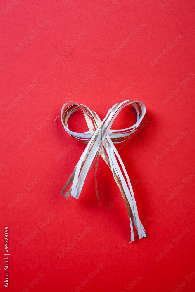 Christmas bow with festive decoration on the red background.