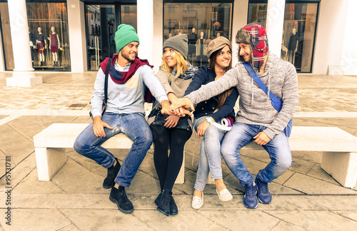 Group of friends hands on top - Teamwork students having fun outdoors - Two couples of young tourists sitting in town square - Beautiful trendy models enjoying life - Concept of friendship and youth