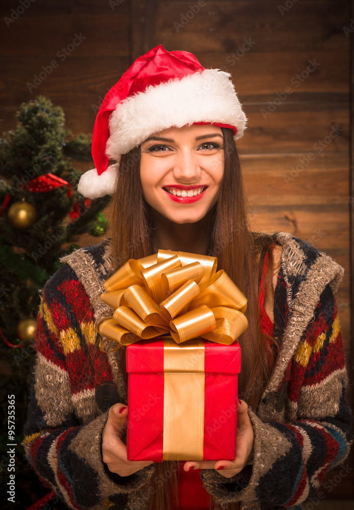 Beautiful girl holding a present near New Year tree