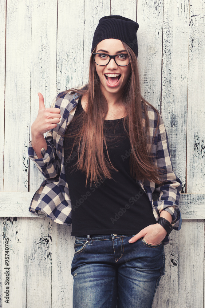 Hipster girl in glasses and black beanie with thumbs up Stock