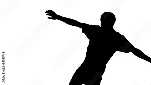 Silhouette of soccer player kicking ball 