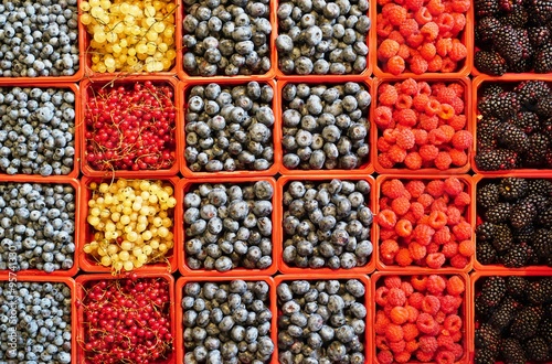 Colorful mixed berries in containers at the farmers market © eqroy