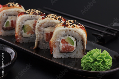 Premium quality sushi rolls with ginger wasabi and soy sauce over black background
