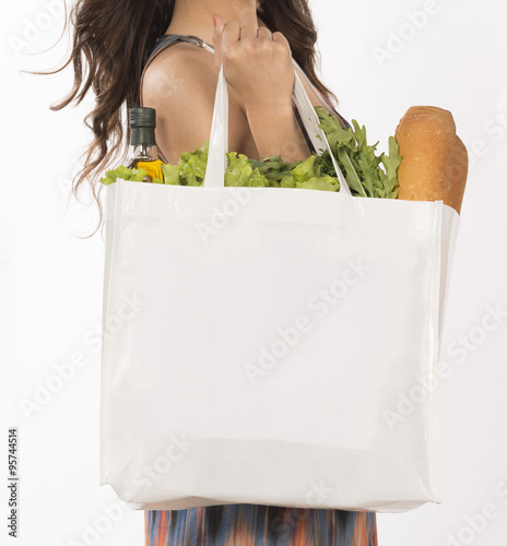 woman holding shopping bag bag full with vegetables on white background. Close-up.