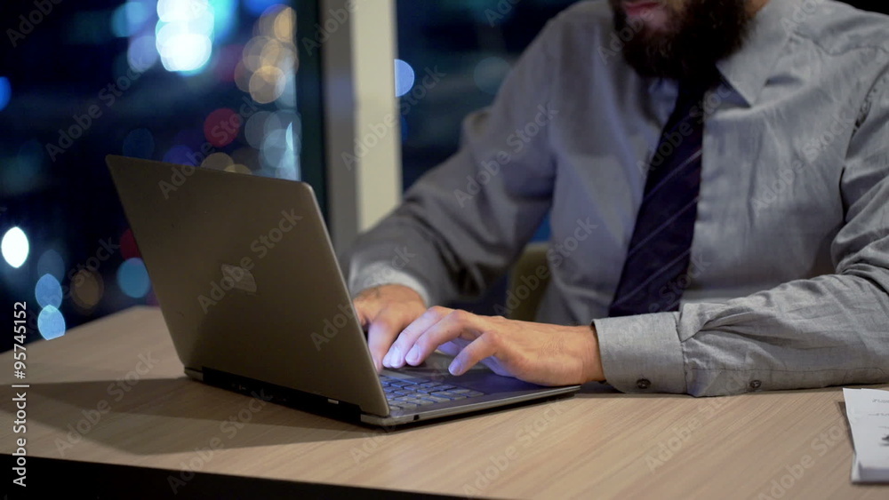Businessman working on laptop by desk in office at night
Businessman working on laptop by desk in office at night