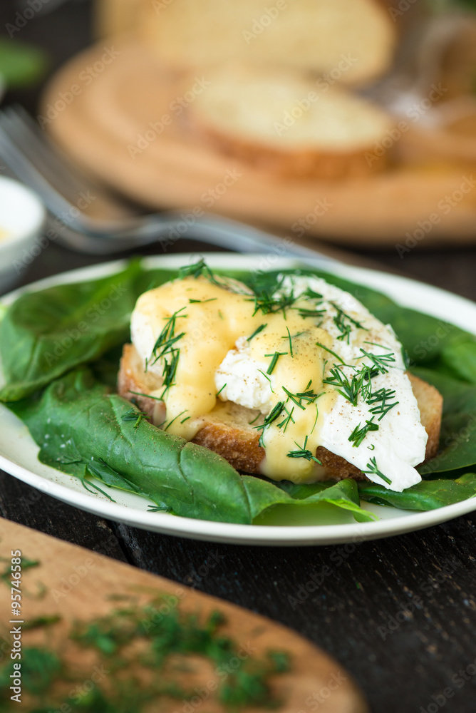Poached egg on a piece of bread with spinach on the wooden table