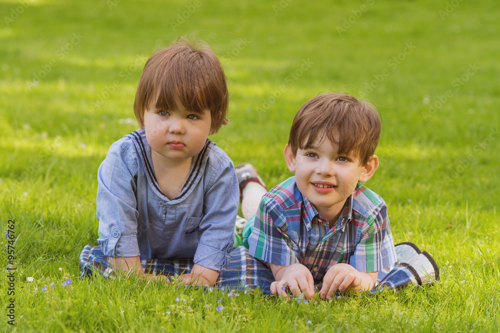two little brothers laying in grass two little brothers laying in grass