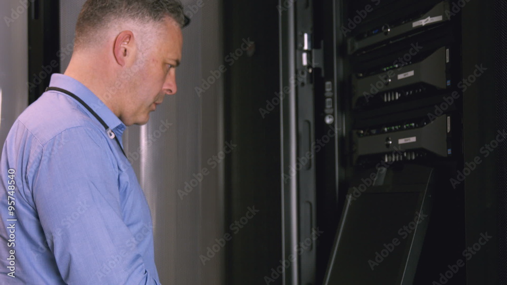 Technician using laptop to analyse server Technician using laptop to analyse server