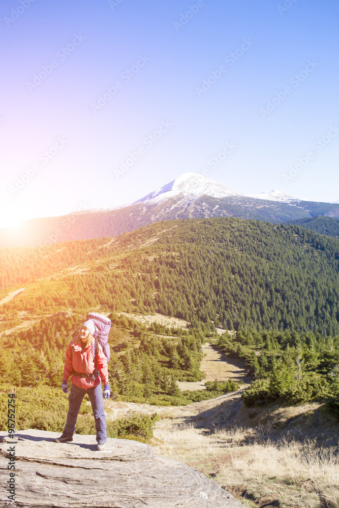 Girl with a backpack standing on a rock.