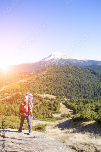 Girl with a backpack standing on a rock.