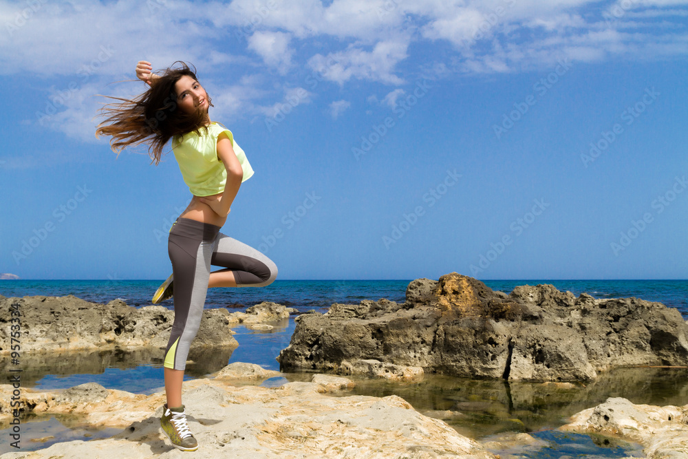 Athletic dark haired teenage girl working out by the ocean.