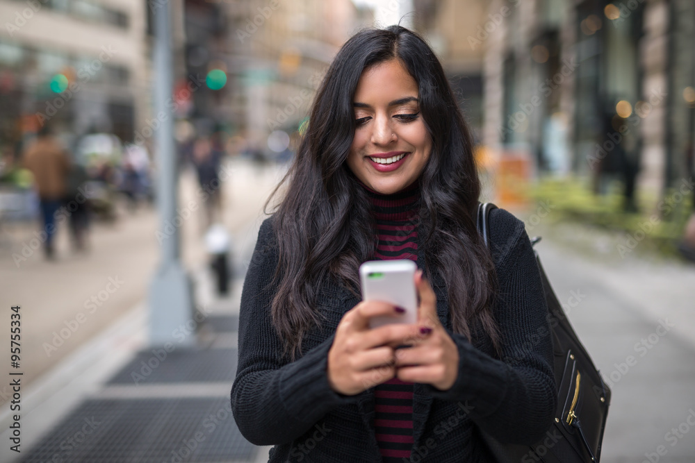 Indian woman in city texting cell phone