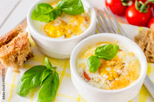 Egg cocotte  in white ramekin with tomato and basil