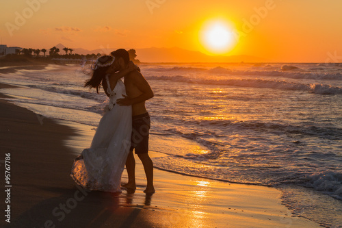 Newly wed young couple on a hazy beach at dusk.