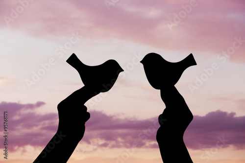 Silhouettes of hands with decorative birds