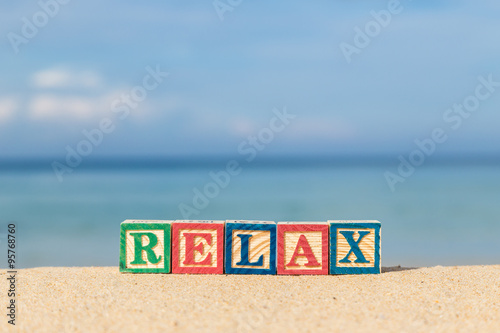 word RELAX in colorful alphabet blocks on tropical beach