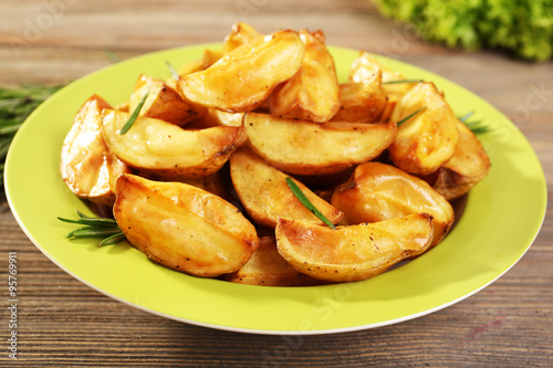 Baked potato wedges on wooden table, closeup