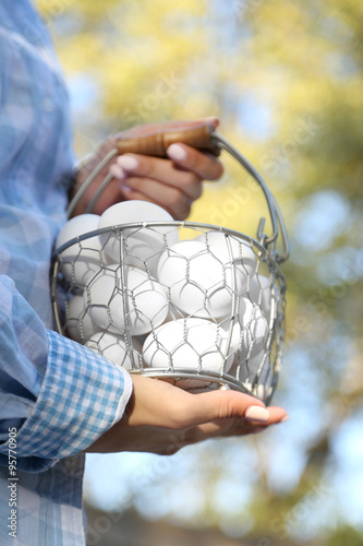 Eggs in basket in women hands outdoors